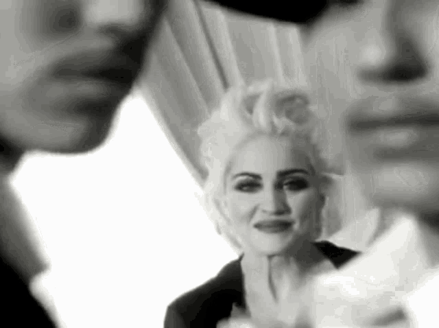 a black and white photo of a woman standing next to two men .