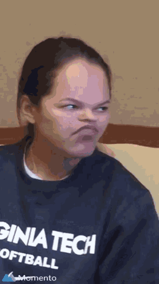 a woman wearing a virginia tech softball shirt makes a funny face