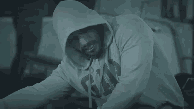 a man wearing a hooded sweatshirt is sitting on the floor .