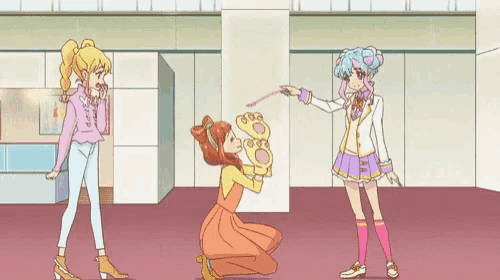 three anime girls are standing in a room and one girl is kneeling down