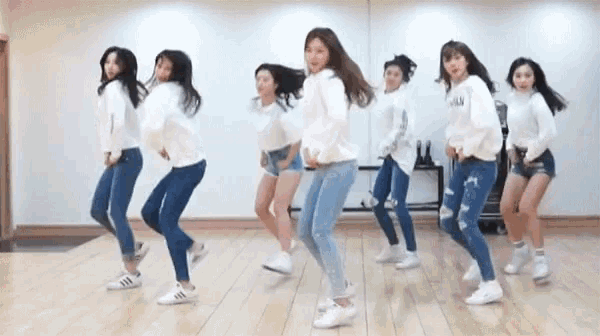 a group of young women are dancing in a room with a white wall .
