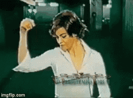 a woman in a white shirt is flexing her muscles in a gif