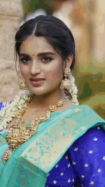 a close up of a woman wearing a blue blouse and a blue saree .