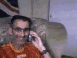 a man wearing a red shirt that says express is talking on a cellphone
