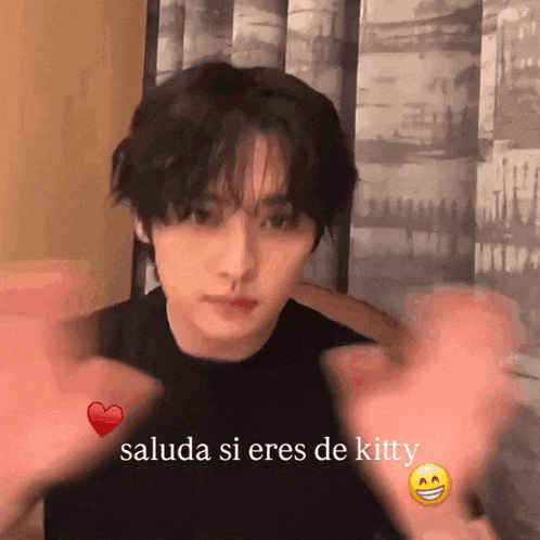 a young man is making a heart with his hands and says " saluda si eres de kitty " on the bottom