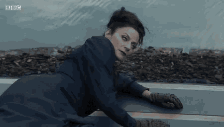 a woman in a blue dress and gloves is laying on the floor .