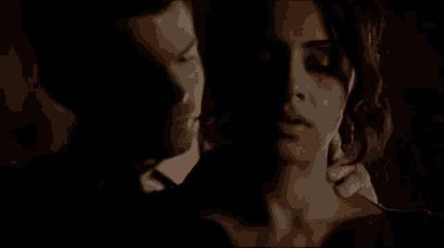 a man is holding a woman 's neck in the dark .