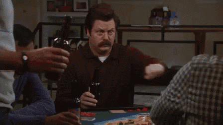a man is sitting at a table playing a game of poker while holding a bottle of beer .