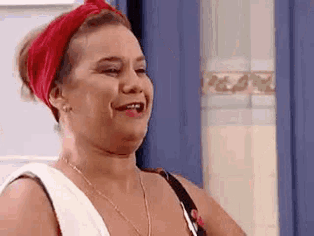 a woman wearing a red headband and a white shirt is smiling and looking at the camera .