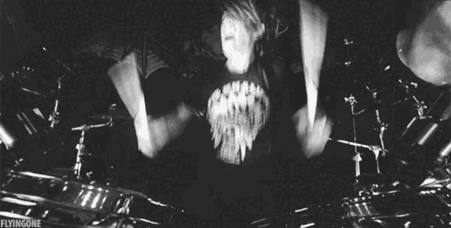 a black and white photo of a man playing drums with the words flyingone written below him
