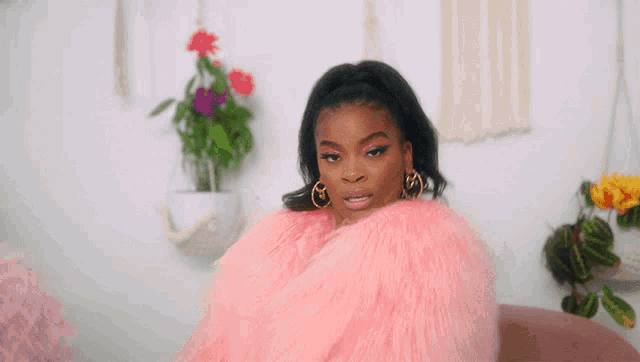 a woman wearing a pink fur coat and earrings looks at the camera