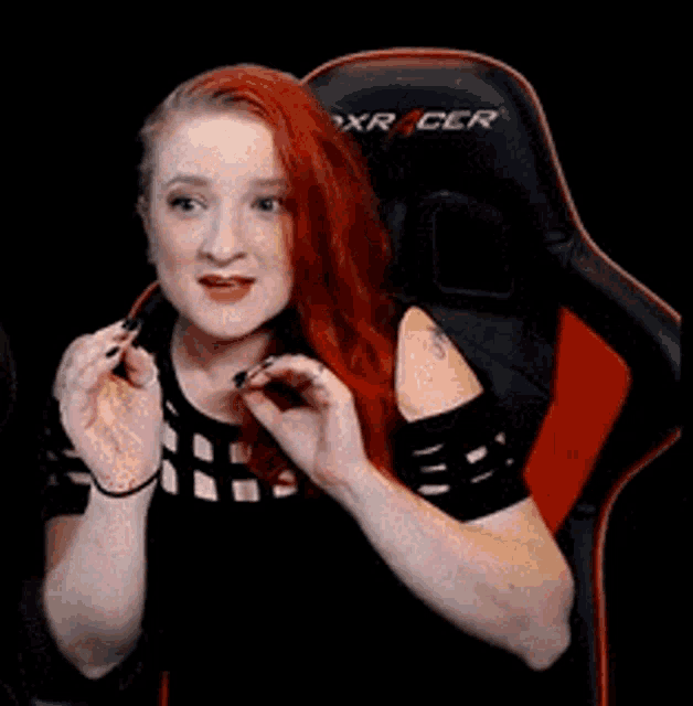 a woman with red hair is sitting in a black and red chair .