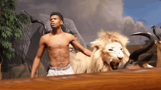 a shirtless man is standing next to a stuffed lion and a goat