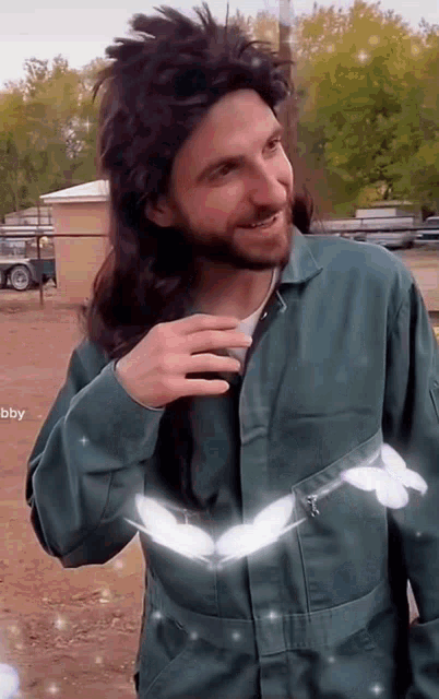 a man with a beard and long hair is wearing a green jacket