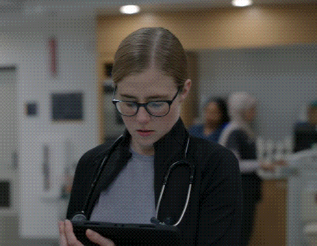 a woman with glasses and a stethoscope around her neck is looking at a tablet