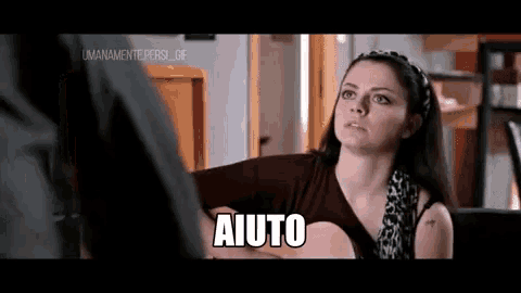 a woman is playing a guitar and says " aiuto " in front of a man .