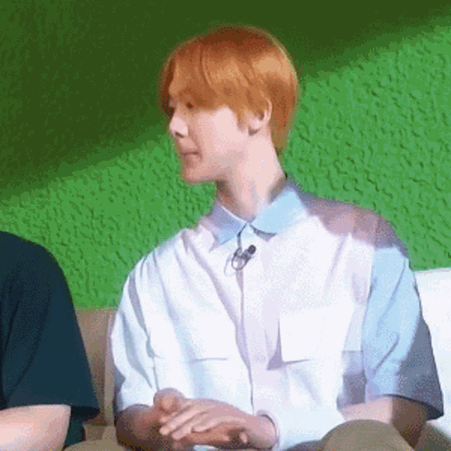 a young man with red hair is sitting on a couch .