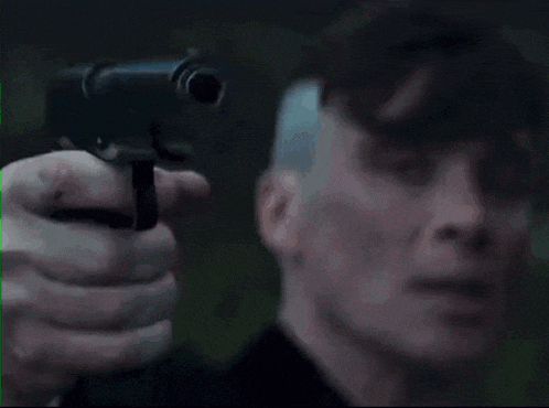 a man in a suit and tie holds a gun in his hand