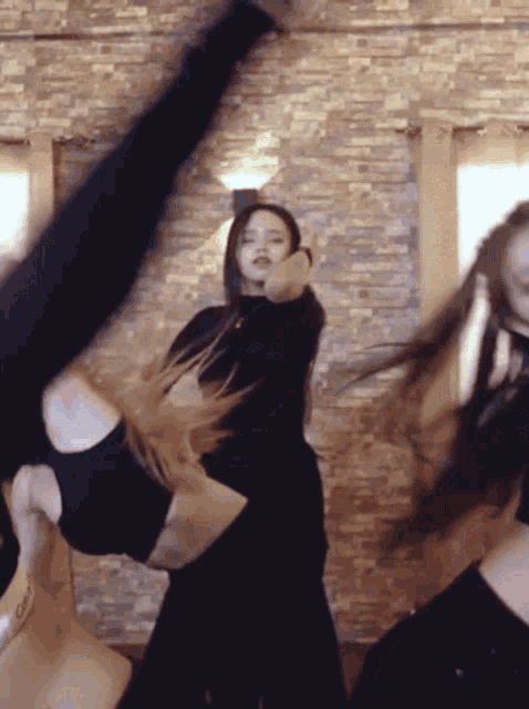 a group of young women are dancing in front of a stone wall