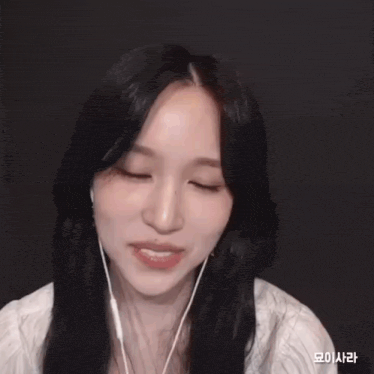 a woman wearing earbuds and a white shirt smiles