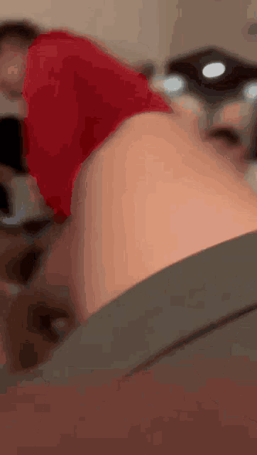 a blurry picture of a person laying on a bed with a red shirt on