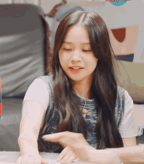 a girl with long hair is sitting on a couch with a sticker that says ' a ' on it