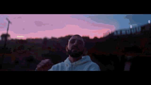 a man with glasses and a beard is covering his face with his hands