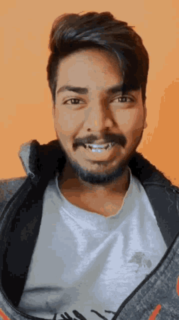 a man with a beard is smiling and wearing a white shirt