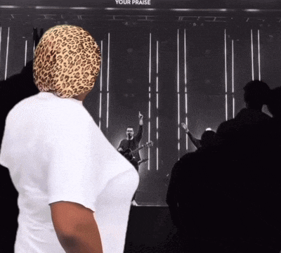a woman wearing a leopard print head scarf stands in front of a sign that says your praise