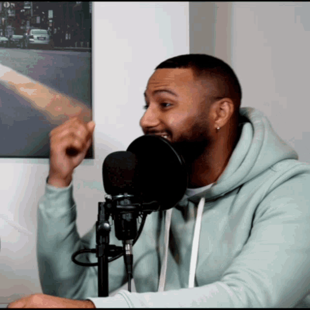 a man in a light blue hoodie is talking into a microphone