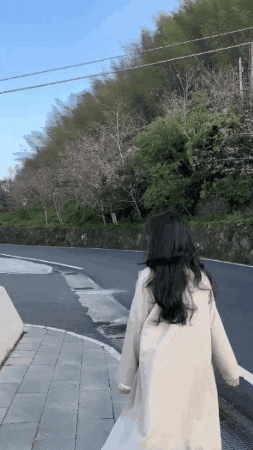 a woman in a white coat walks down a street