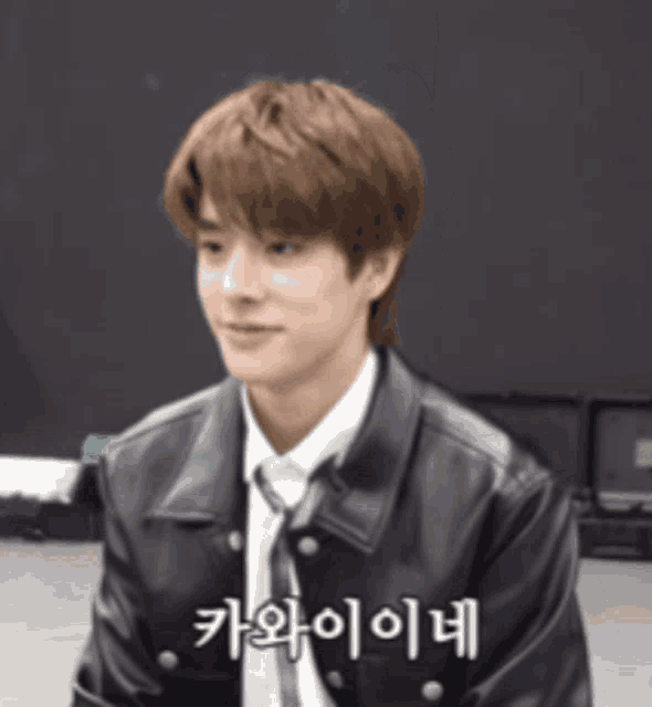 a young man wearing a leather jacket and tie is smiling in korean