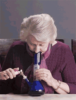 a woman in a purple sweater is smoking a blue bong