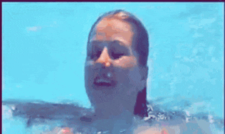 a woman is swimming in a pool wearing a pink bikini .