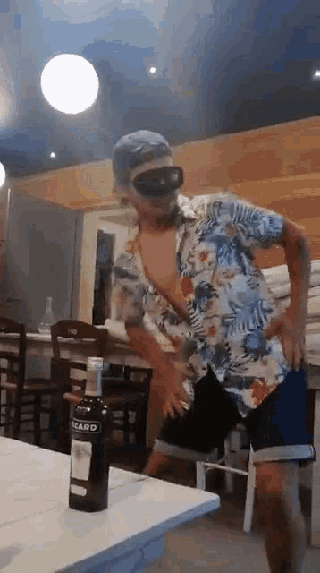 a man is dancing in a restaurant with a bottle of bacardi on the table