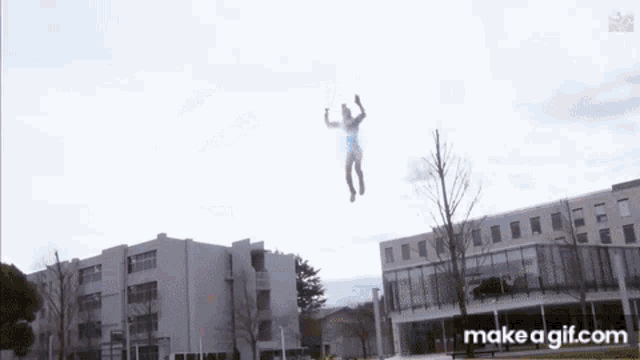 a person is flying through the air in front of a building with makeagif.com written on the bottom