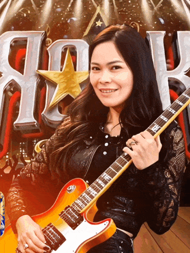 a woman is holding a guitar in front of a rock sign