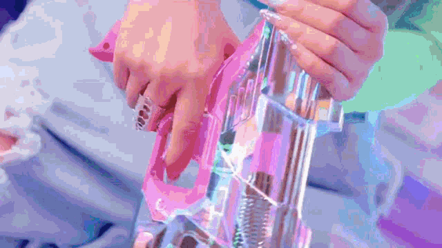 a close up of a person holding a pink and clear toy gun