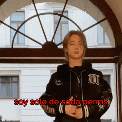 a man standing in front of a window with the words soy solo de soda perras written in red