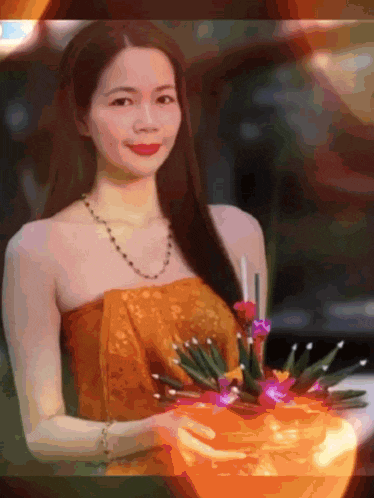 a woman in a gold dress is holding a bowl of candles