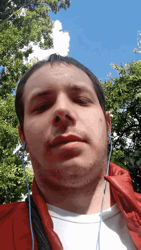 a man wearing headphones and a red jacket is looking at the camera