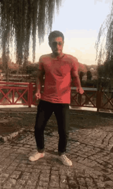 a man in a red shirt is standing on a brick sidewalk