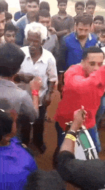 a man in a red shirt is dancing in a crowd of people