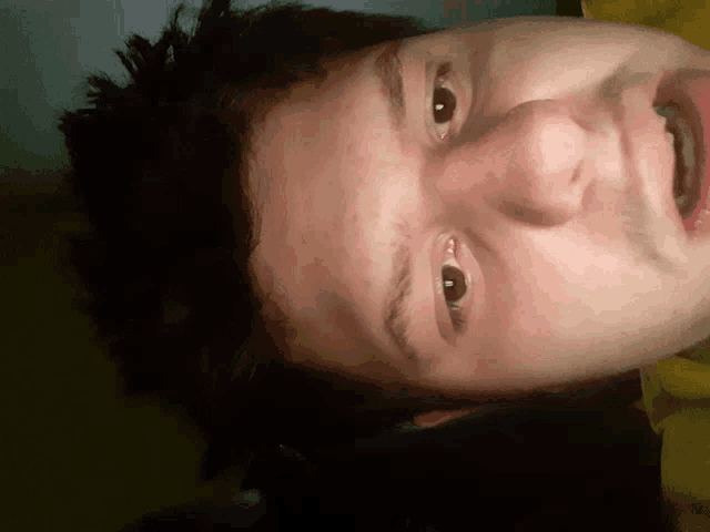 a close up of a person 's face with a yellow shirt on