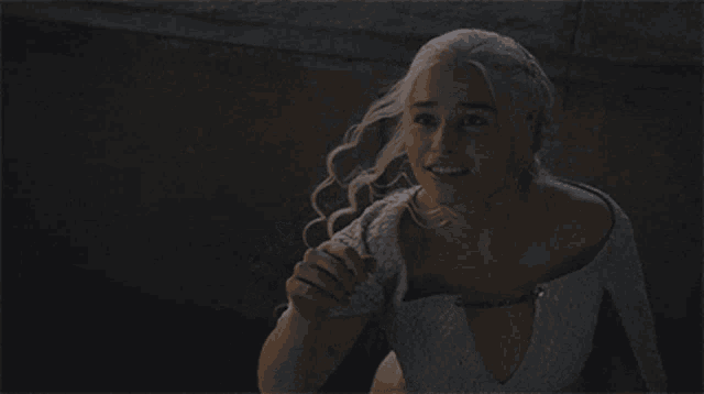a woman in a white dress is smiling and pointing