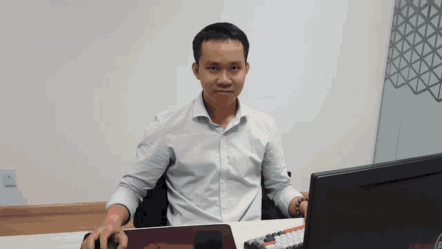 a man is sitting at a desk with a dell computer