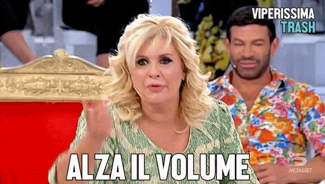 a woman says alza il volume in front of a man in a colorful shirt