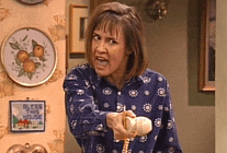 a woman in a blue shirt is holding a cane and pointing at the camera