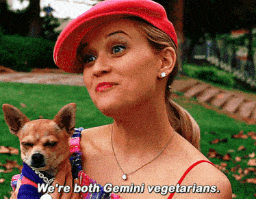 a woman in a red hat holds a small dog and says " we 're both gemini vegetarians "