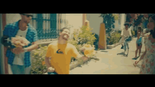 a man wearing a yellow quiksilver shirt is holding flowers